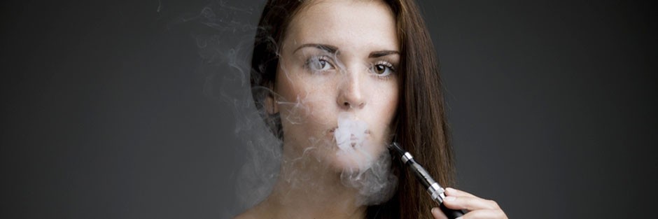 Brunet female is exhaling vapor from an electronic cigarette