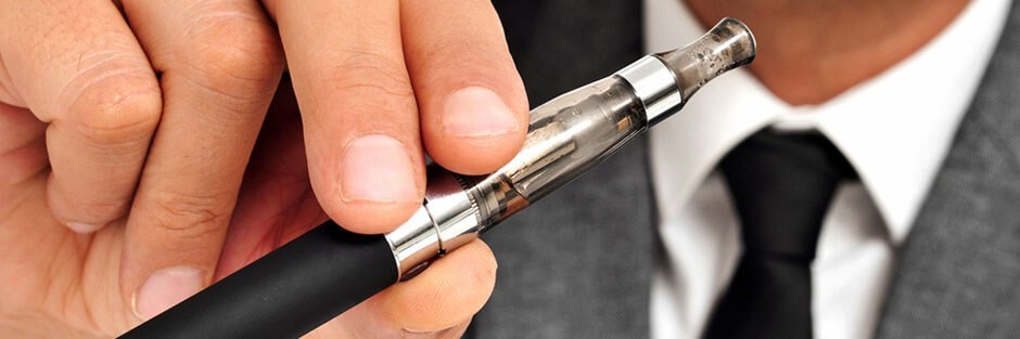 a man in a suit is holding an E Cigarette vape pen