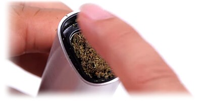 female holding Pax vaporizer while packing in the herbal material and pressing down with her finger