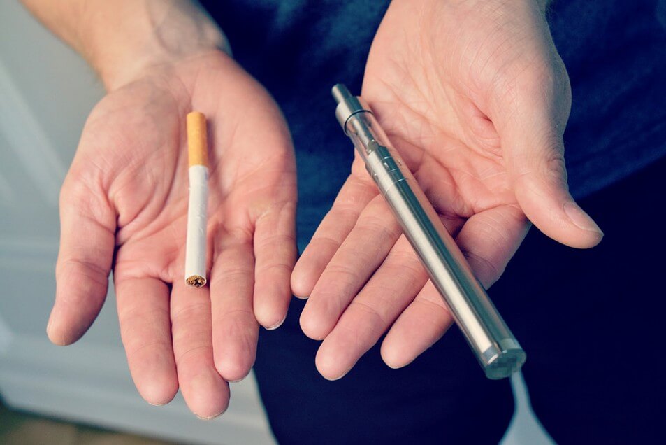 Regular Cigarette nest to a Vaporizer in Palms of Hands