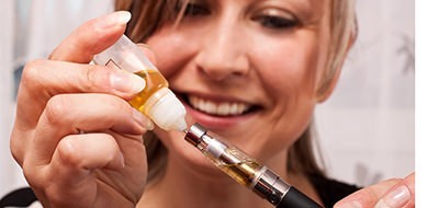 Young Woman fill her Oil Pen with e-Liquid