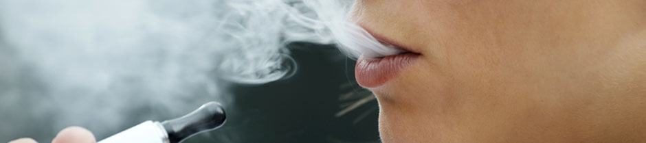 A close up of a woman smoking a vapor pen