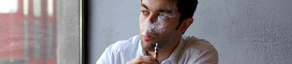 Young man is smoking a marijuana vaporizer pen